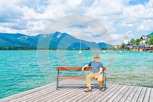 Middle aged male sitting on a bench by the Lake Wolfgangsee, Austria