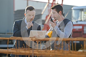 Middle-aged male worker using walkie-talkie with colleague