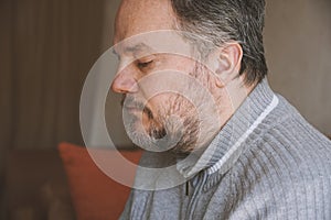 middle-aged man alone at home and looking down and depressed
