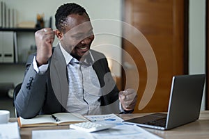 middle aged man American African business man holding computer laptop with hands up in winner is gesture, Happy to be