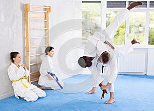 Middle-aged man applying throwing technique on his opponent in sports hall