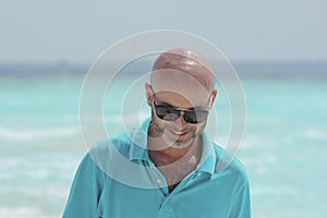 Middle-aged man on the beach in turquoise shirt