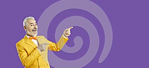 Handsome middle age man pointing away side with his finger isolated purple background. Spase for your advertisement.