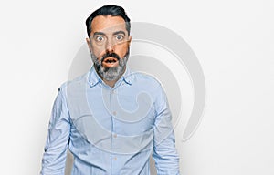 Middle aged man with beard wearing business shirt afraid and shocked with surprise and amazed expression, fear and excited face