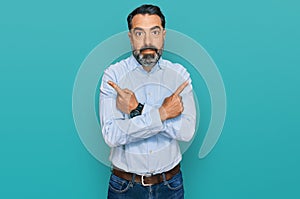 Middle aged man with beard wearing business shirt pointing to both sides with fingers, different direction disagree