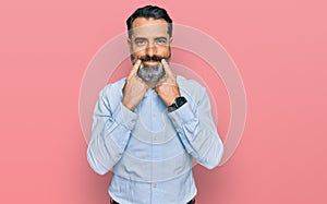 Middle aged man with beard wearing business shirt smiling with open mouth, fingers pointing and forcing cheerful smile