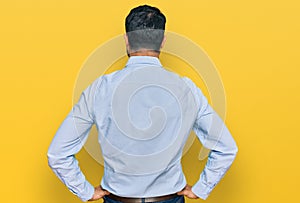 Middle aged man with beard wearing business shirt standing backwards looking away with arms on body