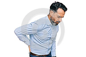 Middle aged man with beard wearing business shirt suffering of backache, touching back with hand, muscular pain