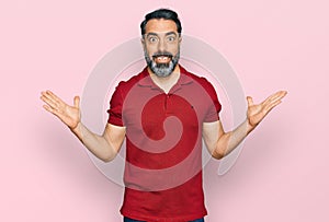 Middle aged man with beard wearing casual red t shirt celebrating victory with happy smile and winner expression with raised hands