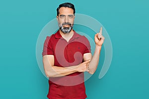 Middle aged man with beard wearing casual red t shirt smiling happy pointing with hand and finger to the side