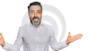 Middle aged man with beard wearing casual white shirt celebrating victory with happy smile and winner expression with raised hands