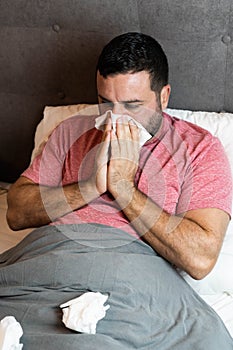 Middle-aged man in bed sick with flu symptoms