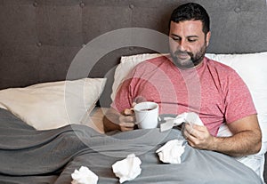 Middle-aged man in bed sick with flu symptoms