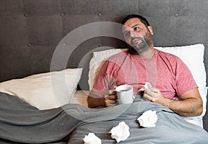 Middle-aged man in bed sick with flu symptoms