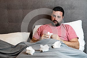 Middle-aged man in bed sick with flu symptoms