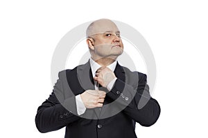 A middle-aged man in a black suit straightens his tie. Isolated on white background