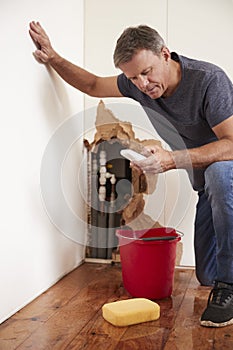 Middle aged man with a burst pipe dialling phone for help