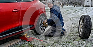 Middle aged man changing tires at home