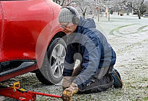 Middle aged man changing tires at home