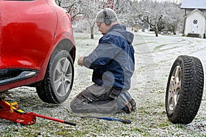 Middle aged man changing tires at home