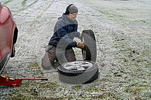 Middle aged man changing tires at home