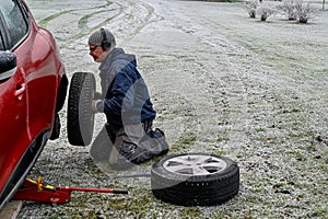 Middle aged man changing tires at home