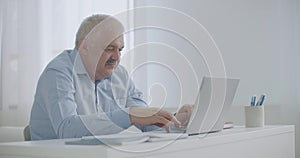 Middle-aged man is communicating using email technology on laptop with internet, typing messages, working from home