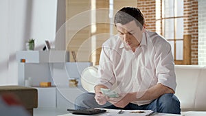 Middle-aged man counting money, planning budget for mortgage and utilities