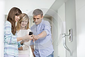 Middle-aged man with daughters using smart phone at home