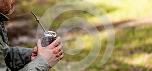 Middle aged man drinking yerba mate in nature. Travel and adventure concept. Latin American drink yerba mate