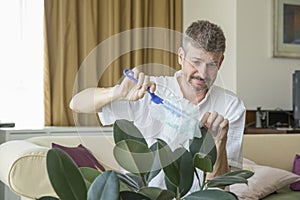 Middle aged man dusting a plant