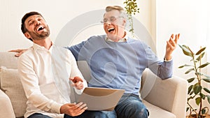 Middle-Aged Man And Elderly Father Using Laptop Sitting Indoor, Panorama
