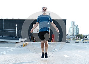 Middle-aged man exercising with jump-rope outdoors.