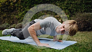 Middle aged man exercising outdoors in garden, doing push ups.. Concept of workout routine at home.