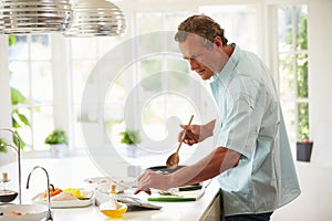 Middle Aged Man Following Recipe On Digital Tablet photo