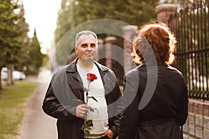 A middle-aged man gives a rose to a woman, romantic date