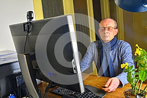 Middle aged man with glasses sitting at desk. Mature man using personal computer. Senior concept. Man working at home