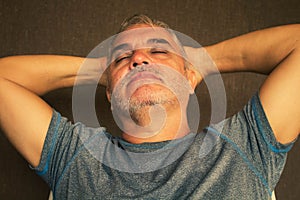 Middle-aged man with gray hair holding his hands behind his head and feeling worried and stressed