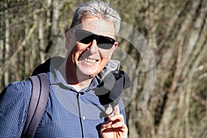 Middle-aged man hiking through the nature in a spring time with a big nice smile