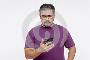 A middle aged man looking confounded and stumped while looking at his cellphone. Wearing eyeglasses and a purple waffle shirt, photo