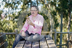 Middle-aged man looking at his cell phone on a parke bench