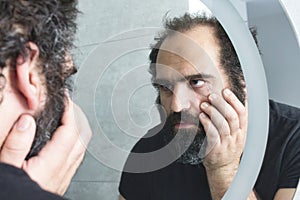 Muž hledá unavený a deprimovaný v koupelna zrcadlo 