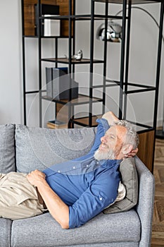 Middle-aged man lying down on the sofa and rests