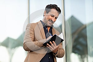 Middle aged man manager taking notes in notepad outdoors