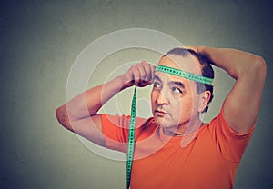 Middle aged man measuring diameter of his head photo