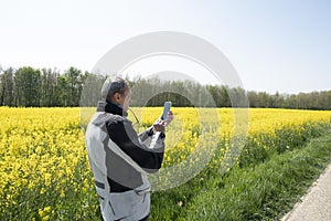 a middle-aged man motorcyclist stands on field flowering yellow rapeseed