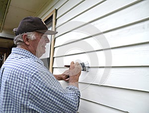 Middle-aged Man Painting Weatherboards.