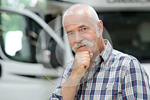 Middle aged man posing in front camping van