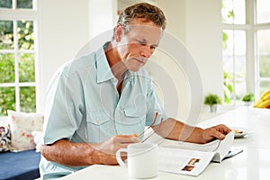 Middle Aged Man Reading Magazine Over Breakfast photo