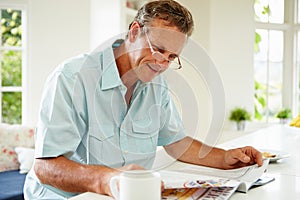 Middle Aged Man Reading Magazine Over Breakfast